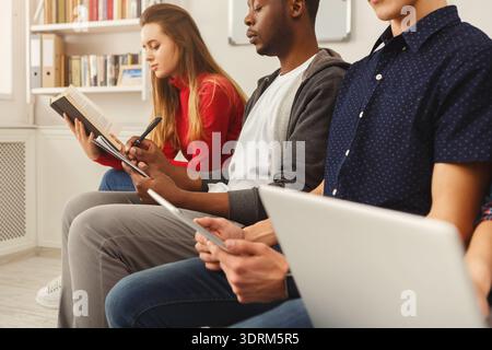 Group of People Engaged in Reading and Using Devices in a Study Space Stock Photo