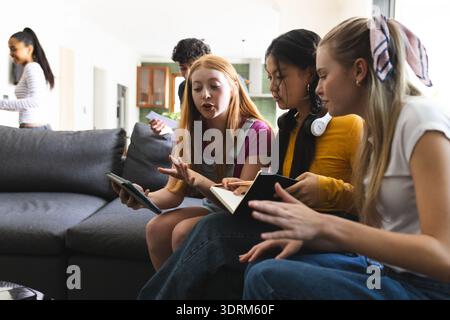 Teenagers discussing project on tablet and notebook while sitting on couch at home. collaboration, technology, studying, brainst Stock Photo