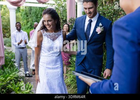 Bride and groom walking down aisle, smiling joyfully at outdoor wedding ceremony. marriage, celebration, romance, happiness, bri Stock Photo