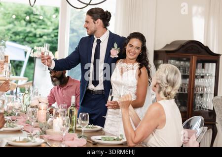 Bride and groom toasting with guests at elegant wedding reception indoors. celebration, marriage, formal, party, luxury, romance Stock Photo