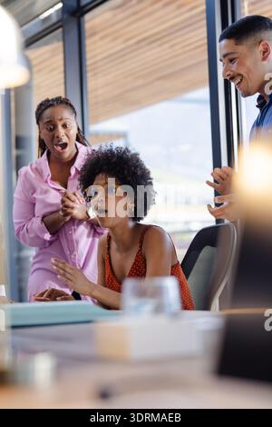 In office, African American woman surprised by colleagues, celebrating exciting news. Celebration, teamwork, happiness, exciteme Stock Photo