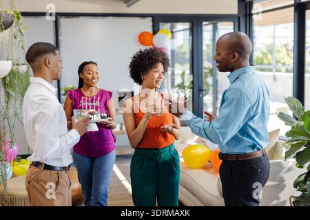 At office celebration, African American colleagues having drinks and talking together. teamwork, collaboration, diversity, workp Stock Photo