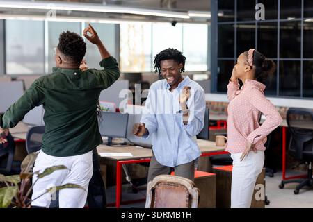 In office, colleagues celebrating successful project, dancing joyfully together. Teamwork, collaboration, achievement, celebrati Stock Photo