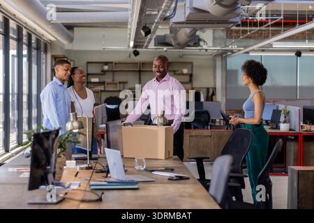 Colleagues in office smiling and discussing project around desk with laptops. Business, teamwork, collaboration, professional, b Stock Photo