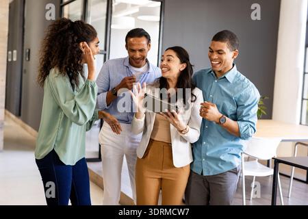 Business team collaborating and laughing while using tablet in modern office. Collaboration, teamwork, digital, technology, brai Stock Photo