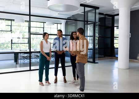 Diverse business team discussing project in modern office, standing and smiling. Teamwork, collaboration, corporate, innovation, Stock Photo