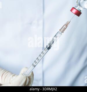 Close up of gloved hands holding a syringe with precise measurement for medical Stock Photo