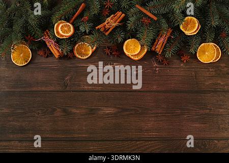 Fresh fir branches with dried oranges, star anise, cinnamon, and pine cones on a wooden table. Christmas composition and New Yea Stock Photo