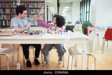 A teacher guiding students in a robotics project during a STEM class in the library Stock Photo