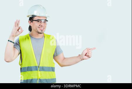 Latin young engineer recommending and pointing side isolated. Cheerful and friendly engineer pointing at promotion isolated Stock Photo