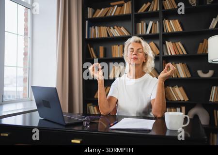 Yoga mindfulness meditation No stress keep calm. Middle aged woman practicing yoga at office. Woman taking break from work medit Stock Photo