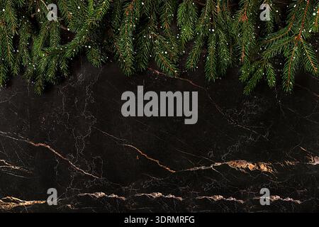 Christmas and New Year 2024 background with fir branches covered with snowflakes on dark marble table, banner for holiday screen Stock Photo