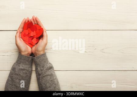 Hands Hold Red Paper Hearts Creating a Collage on a Wooden Table Stock Photo