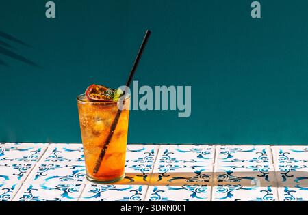 A cool cup of fruit soda with ice cubes on the table with patterned tiles Stock Photo