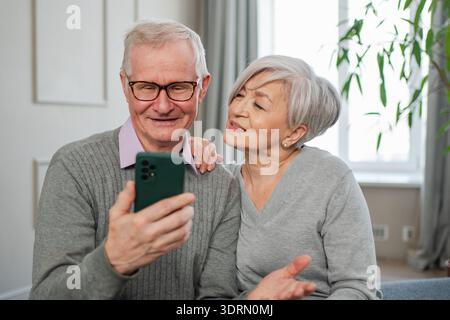 Video call. Happy senior couple woman man with smartphone having video call. Mature old grandmother grandfather talking speaking Stock Photo