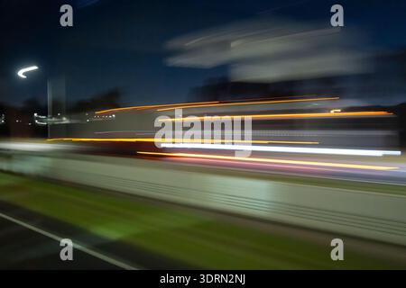 Light trails of a moving vehicle at night on the road Stock Photo