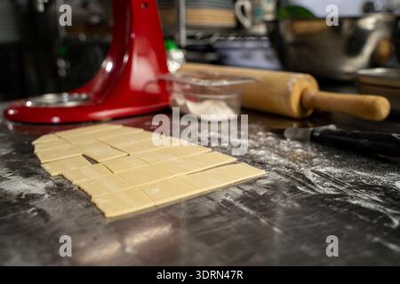 Close up of dough squares on floured stainless steel counter. Stock Photo