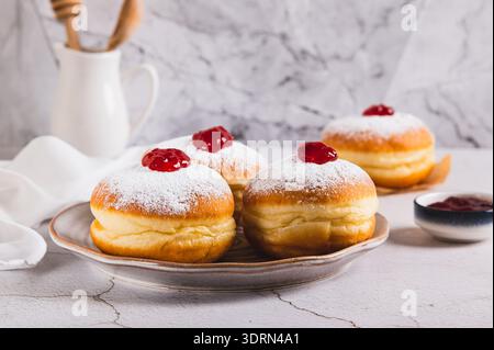 Sweet donuts in powdered sugar with jam on a plate on the table Stock Photo