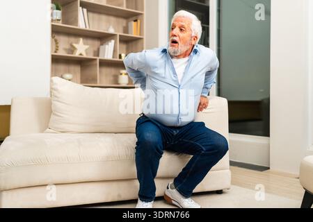 Backache back pain. Unhappy senior old man suffering from backache at home. Upset elder man feel sudden back pain muscles ache t Stock Photo