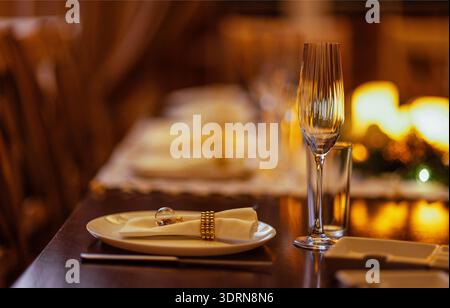 Elegant dining table set with white plates, sparkling glassware, and decorative napkins, creating a warm and inviting atmosphere Stock Photo