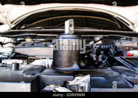 Car Engine Mount Replacement, A new, black hydraulic engine mount sits on the radiator support, ready for installation to reduce engine vibration and Stock Photo