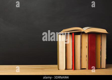 Collection of Books on a Wooden Table Against a Black Background for Educational Purposes Stock Photo