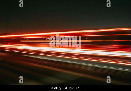Light trails of a moving vehicle at night on the road Stock Photo
