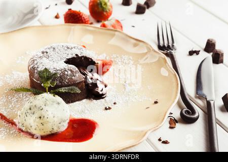 Chocolate Dessert Served With Ice Cream on a Plate With Strawberries and Chocolate Pieces Around Stock Photo