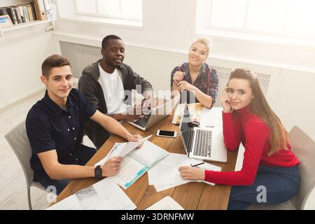 Group of Students Working Together on Projects at a Study Table in a Bright Room Stock Photo