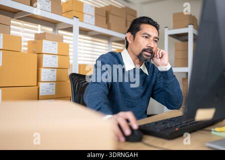 Warehouse manager analyzing data on desktop computer, planning inventory and business operations Stock Photo