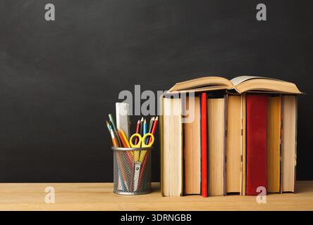 Collection of Books and Stationery on a Wooden Desk in a Basic Learning Environment Stock Photo
