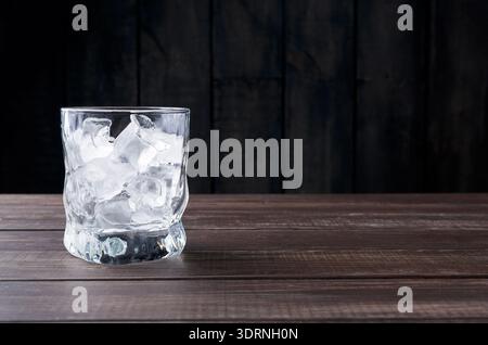 Clear Glass Filled With Ice Cubes on Wooden Table in a Dim Setting During the Evening Stock Photo
