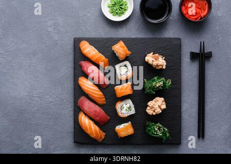 Enjoying Sushi Served on a Black Slate Board With Chopsticks and Condiments Stock Photo