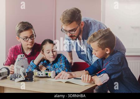 Children and Teacher Collaborating on Robotics Project During a Classroom Activity in the Afternoon Stock Photo