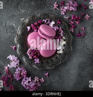 Blackberry macarons on vintage plate and lilac flowers over grey texture background Stock Photo
