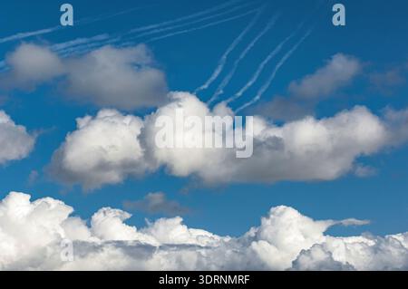 Fleecy or cumulus clouds with vapour trails in the sky Stock Photo
