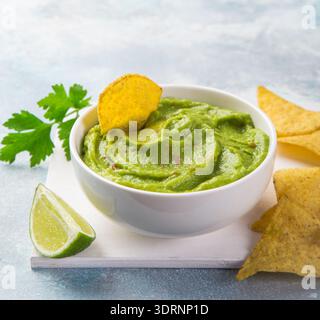 Avocado guacamole with tortilla chips in white bowl Stock Photo
