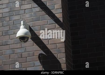 Security camera mounted on a brick wall in daylight Stock Photo