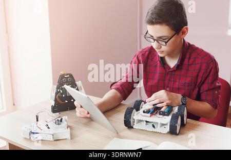 Student Works on Robot Project at Desk With Tablet and Parts During a School Activity Stock Photo