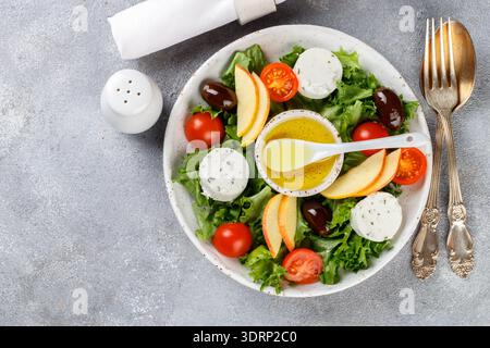 Fresh goat cheese salad with lettuce, cherry tomatoes, Apple, Kalamata olives and a dressing of olive oil. Copy space top view Stock Photo