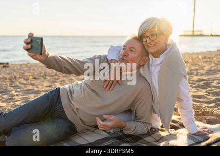 Video call. Senior couple making selfie having video call on beach outdoor. Mature old grandmother grandfather talking speaking Stock Photo