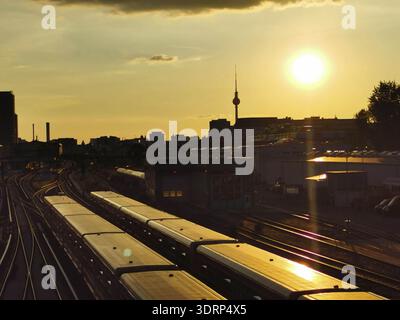 Sunset over train tracks with urban silhouette and Berlin TV tower in the background, Berlin Stock Photo