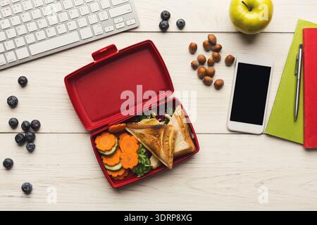 Lunch Ideas in a Lunchbox With Fruits and Vegetables on a Desk With a Keyboard and Phone Stock Photo
