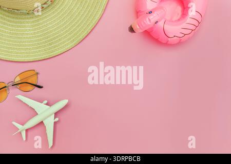 Summer beach composition. Minimal simple flat lay with plane sunglasses hat and Inflatable flamingo isolated on pastel pink back Stock Photo