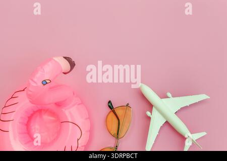 Summer beach composition. Minimal simple flat lay with plane sunglasses and Inflatable flamingo isolated on pastel pink backgrou Stock Photo