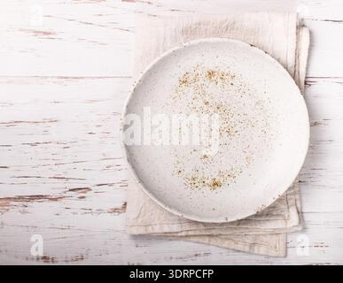 Cooking background with empty light plate and linen napkin on white wooden table. Rustic style. Selective focus. Top view, copy Stock Photo
