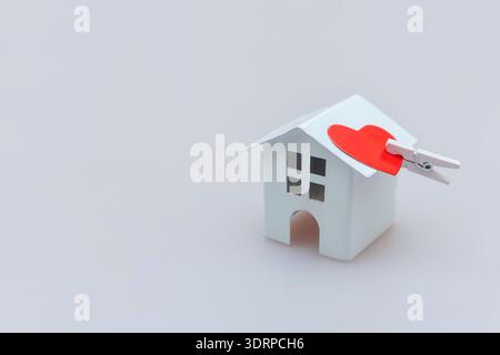 Simply minimal design with miniature white toy house with red heart isolated on white background Stock Photo