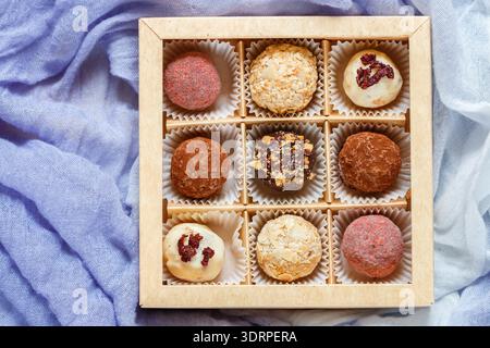 Assorted truffle set  of dark and white chocolate with almonds, hazelnuts and dried cranberries or cherries in a paper box. Cand Stock Photo