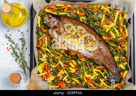 Baked fish trout with vegetables (potatoes, carrots, string beans, green peas and onions) with lemon, thyme and pink pepper. Wil Stock Photo