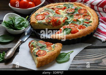 Summer outdoor tart, pie of fresh vegetables - tomatoes, spinach and red onion with cream and cheese. Selective focus Stock Photo
